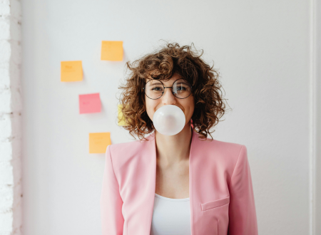Woman in an office blowing a bubble with chewing gum.