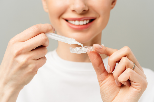 Woman putting bleaching gel in a custom whitening tray.
