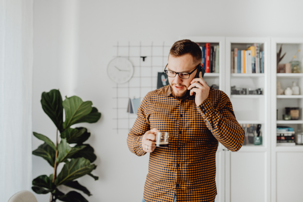A man holding a cup of coffee and talking on the phone.